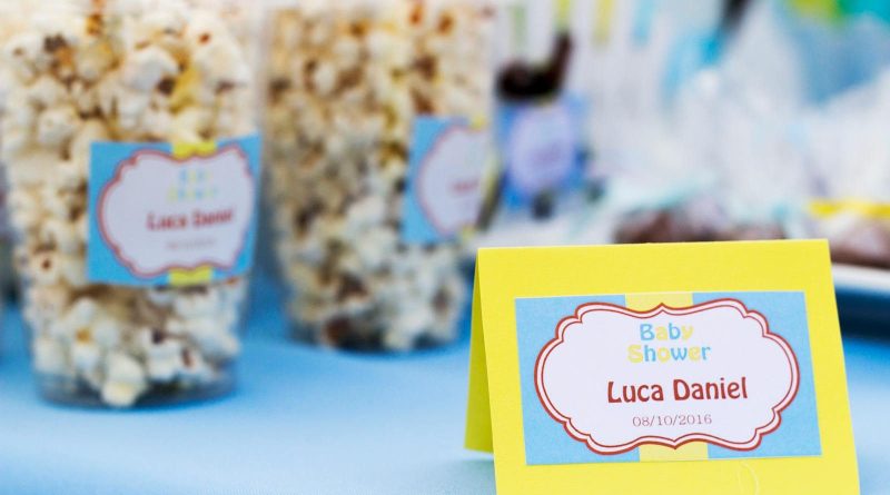 Popcorn treats with colorful labels at a baby shower celebration table.
