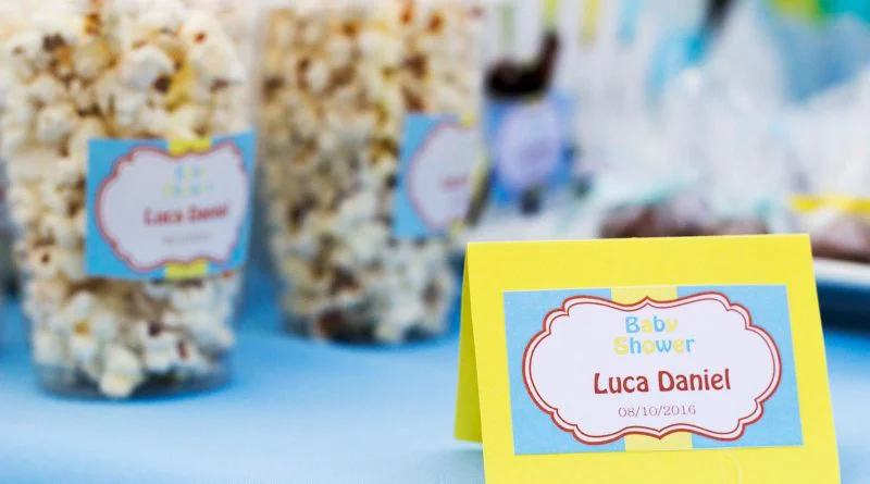 Popcorn treats with colorful labels at a baby shower celebration table.