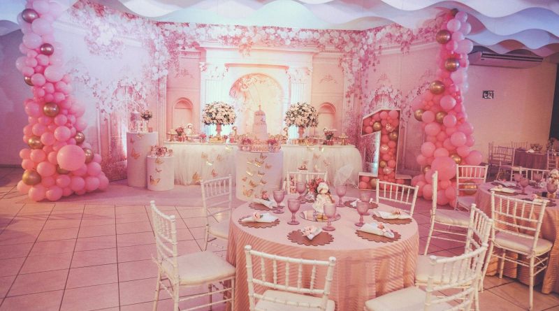 A beautifully decorated pink themed birthday party with floral arrangements and balloon arches.