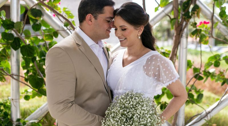 Bride and groom smiling and embracing in a lush garden setting on their wedding day.