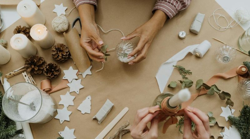 Top view of a Christmas DIY craft table with candles, baubles, and decorations in progress.