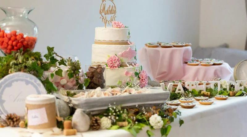 A beautifully decorated dessert table featuring a floral wedding cake and various sweets, perfect for celebrations.