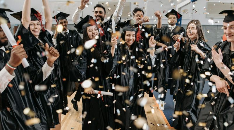 A diverse group of graduates celebrating with confetti indoors, capturing achievement and joy.