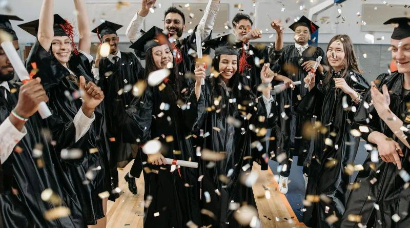 A diverse group of graduates celebrating with confetti indoors, capturing achievement and joy.